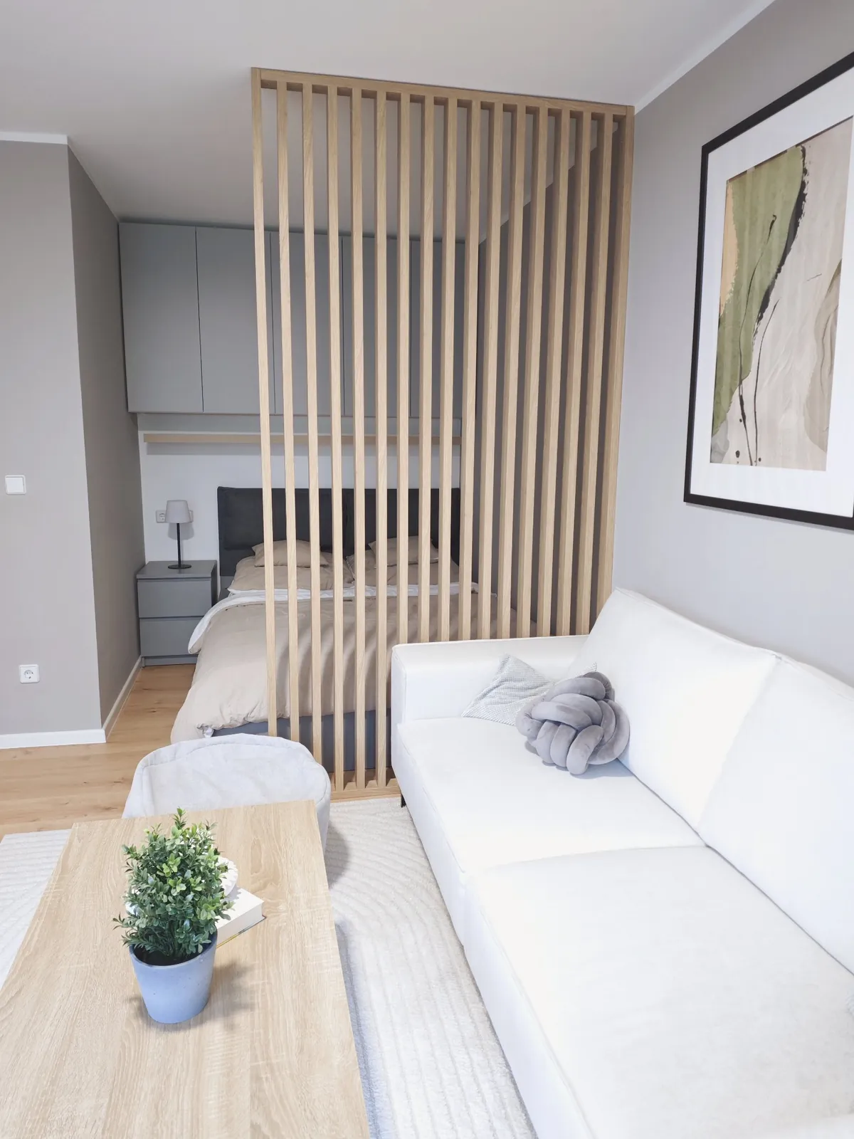 Holzlamellen trennen die Schlafnische vom Wohnbereich mit Sofa